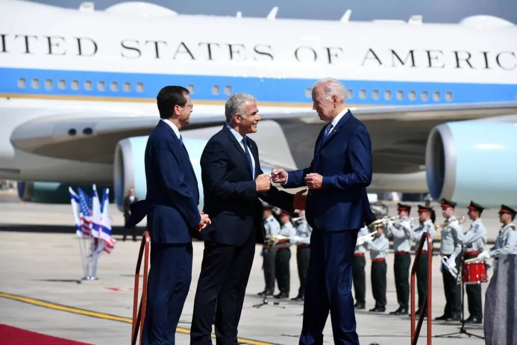 US President Joe Biden (R) is welcomed by Israeli President Isaac Herzog (L) and Israeli Interim Prime Minister Yair Lapid (C) in Tel Aviv, Israel on 13 July 2022